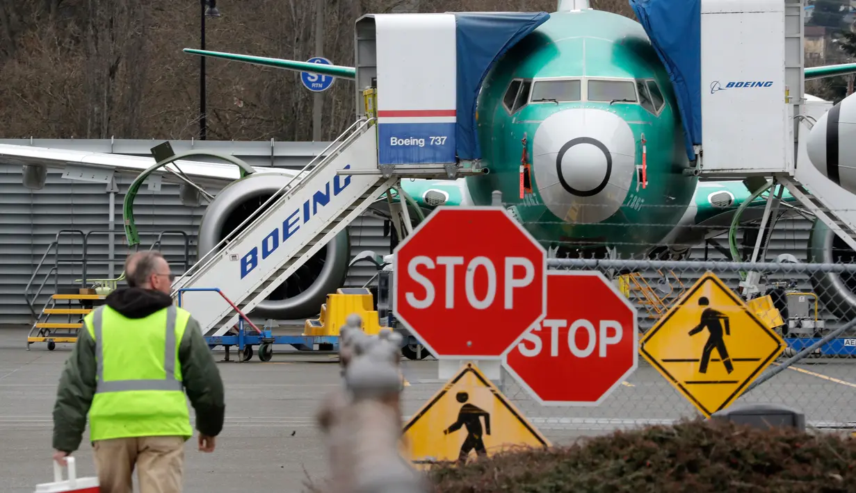 Pekerja Boeing berjalan ke arah  jet 737 Max di Renton, Washington, Senin (16/12/2019). Boeing Co mengumumkan akan menghentikan untuk sementara waktu produksi pesawat jenis 737 MAX – yang sudah dilarang terbang – pada Januari 2020 mendatang. (AP/Elaine Thompson)