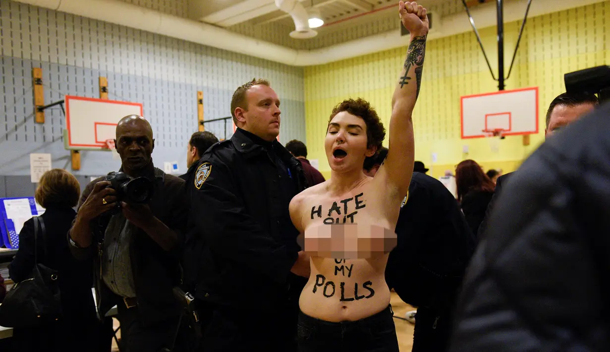 Petugas berusaha membubarkan demonstrasi yang dilakukan dua wanita telanjang dada di TPS Pilpres AS 59, di mana Donald Trump memberikan suaranya di New York, Selasa (8/11). Dalam aksi ini mereka meneriakkan slogan anti-Trump. (REUTERS/Darren Ornitz)