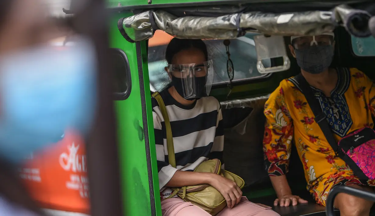 Penumpang yang mengenakan masker duduk di dalam taksi roda tiga di Manila, sehari sebelum pihak berwenang mencabut perintah tinggal di rumah pada Selasa (7/9/2021). Filipina akan mencabut lockdown di ibu kota Manila pada Rabu (8/9), saat kasus corona harian naik dua kali lipat. (Ted ALJIBE/AFP)