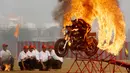 Seorang anggota tentara India dari tim motor 'Tornado' melompati cincin api dengan mengendarai motor selama latihan gabungan di akademi pelatihan perwira di Chennai (9/3). (AFP Photo/Arun Sankar)