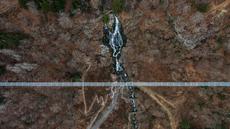 Foto udara yang diambil pada 3 Maret 2023 menunjukkan jembatan gantung yang sedang dibangun, menghadap ke air terjun di Todtnau, barat daya Jerman. Pembangunan jembatan sepanjang 450 meter yang digantung dengan ketinggian hingga 120 meter ini diharapkan selesai pada Mei 2023 dan menjadi daya tarik wisata utama di Black Forest. (PATRICK HERTZOG / AFP)