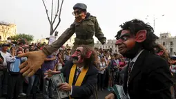 Para demonstran mengenakan kostum pejabat dan topeng sambil menghambur-hamburkan uang berunjuk rasa anti korupsi untuk memprotes pencalonan presiden Peru, Keiko Fujimori di Kota Lima, Peru (5/4). (REUTERS/Guadalupe Pardo)