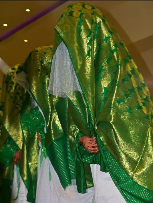 Pengantin wanita berdiri dalam aula pernikahan saat mereka menunggu dimulainya upacara pernikahan massal di Kabul, Afghanistan, 13 Juni 2022. Upacara pernikahan dihadiri ratusan tamu dan pejuang Taliban yang membawa senjata. (Sahel ARMAN/AFP)