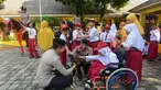 Salah satu siswa didampingi personel Direktorat Polisi Satwa (Ditpolsatwa) berinteraksi dengan anjing pelacak K-9 di Sekolah Luar Biasa Negeri (SLBN) kota Depok, Jawa Barat, Senin (2/6/2025). (merdeka.com/Arie Basuki)