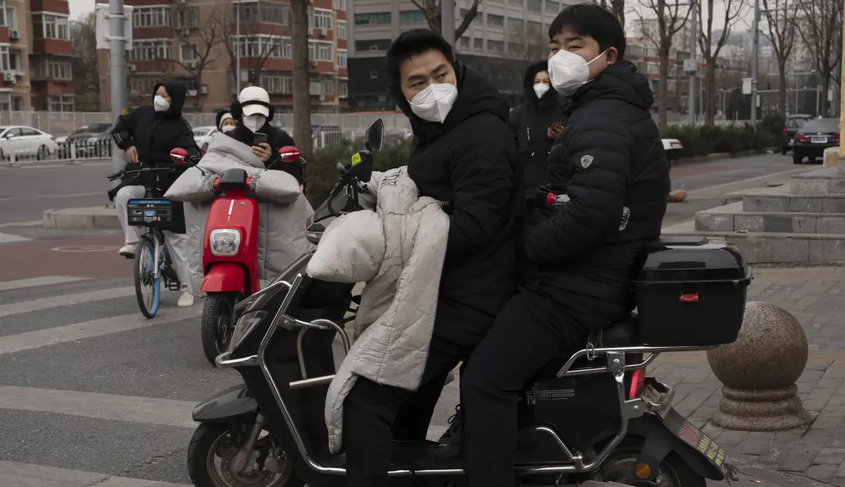 Pengendara skuter dengan masker melintasi persimpangan di Beijing, China, Jumat (2/12/2022). Lebih banyak kota melonggarkan pembatasan, memungkinkan pusat perbelanjaan, supermarket, dan bisnis lainnya dibuka kembali menyusul protes akhir pekan lalu di Shanghai dan daerah lain di mana beberapa orang menyerukan Presiden Xi Jinping untuk mengundurkan diri. (AP Photo/Ng Han Guan)