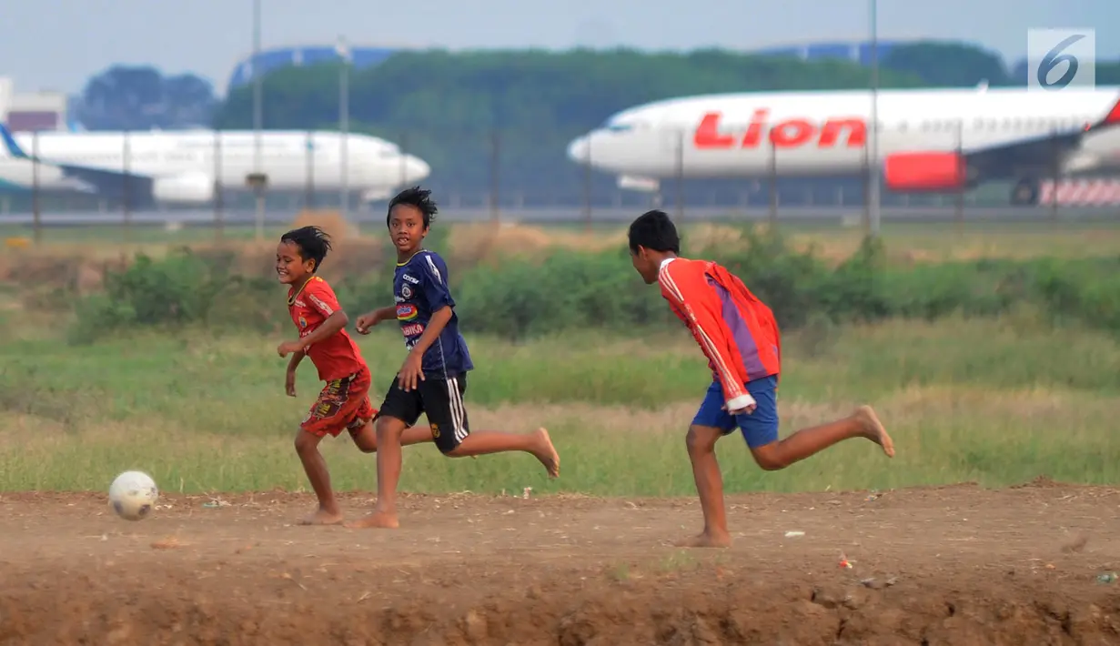 Anak-anak bermain bola di kawasan proyek perluasan landasan pacu atau Runway 3A Bandara Soekarno-Hatta (Soetta), Rawa Bokor, Tangerang, Banten, Selasa (2/7/2019). Mereka memanfaatkan lahan kosong yang belum dikerjakan pihak kontraktor untuk bermain bola. (merdeka.com/Arie Basuki)