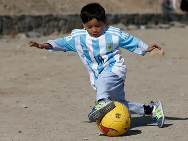 Murtaza Ahmadi (5), bocah asal Afghanistan, memakai jersey yang ditandatangani langsung oleh bintang Barcelona yang juga idolanya, Lionel Messi, ketika bermain sepak bola di sebuah lapangan terbuka di Kabul, Jumat (26/2). (REUTERS/Omar Sobhani)