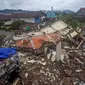 Pengemudi melewati bangunan yang diratakan oleh gempa bumi di Mamuju, Sulawesi Barat, Sabtu (16/1/2021). Petugas Badan Penanggulangan Bencana Daerah (BPBD) masih mendata jumlah kerusakan dan korban akibat gempa bumi tersebut. (AP Photo/Yusuf Wahil)