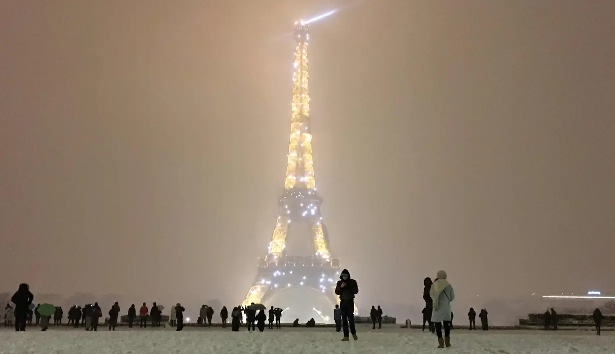 Suasana malam Menara Eiffel saat hujan salju di Paris Prancis (6/2). Ratusan orang terpaksa meninggalkan mobil mereka untuk tidur di tempat penampungan darurat akibat cuaca ekstrem yang melanda. (AFP Photo / Philippe Dupeyrat)