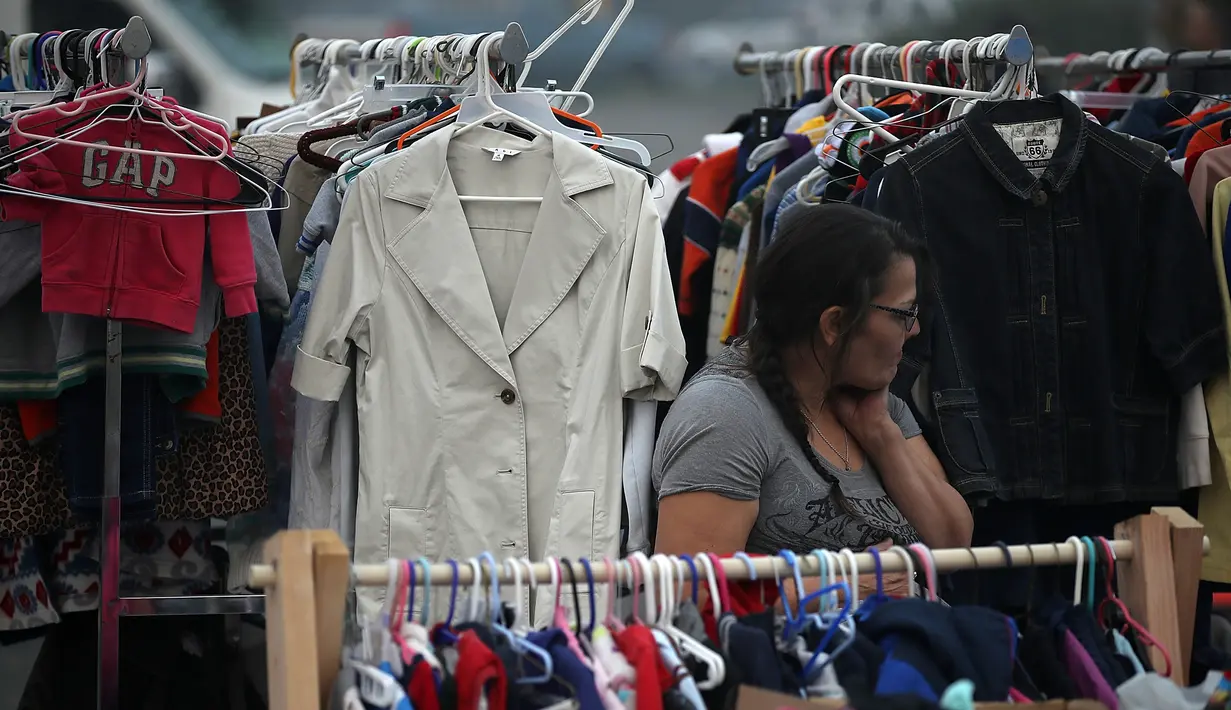 Seorang perempuan mencari pakaian yang disumbangkan di pusat pengungsian di tempat parkir Walmar, Chico, California (16/11). Akibat kebakaran yang terjadi di California sekitar 63 orang tewas. (AFP Photo/Justin Sullivan)