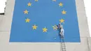 Warga mengamati mural yang menggambarkan seorang pria tengah menghancurkan salah satu dari 12 bintang kuning bendera Uni Eropa di dinding kawasan Dover, Inggris, Senin (8/5). Mural karya seniman jalanan Banksy itu berjudul 'Brexit'. (Gareth Fuller/via AP)