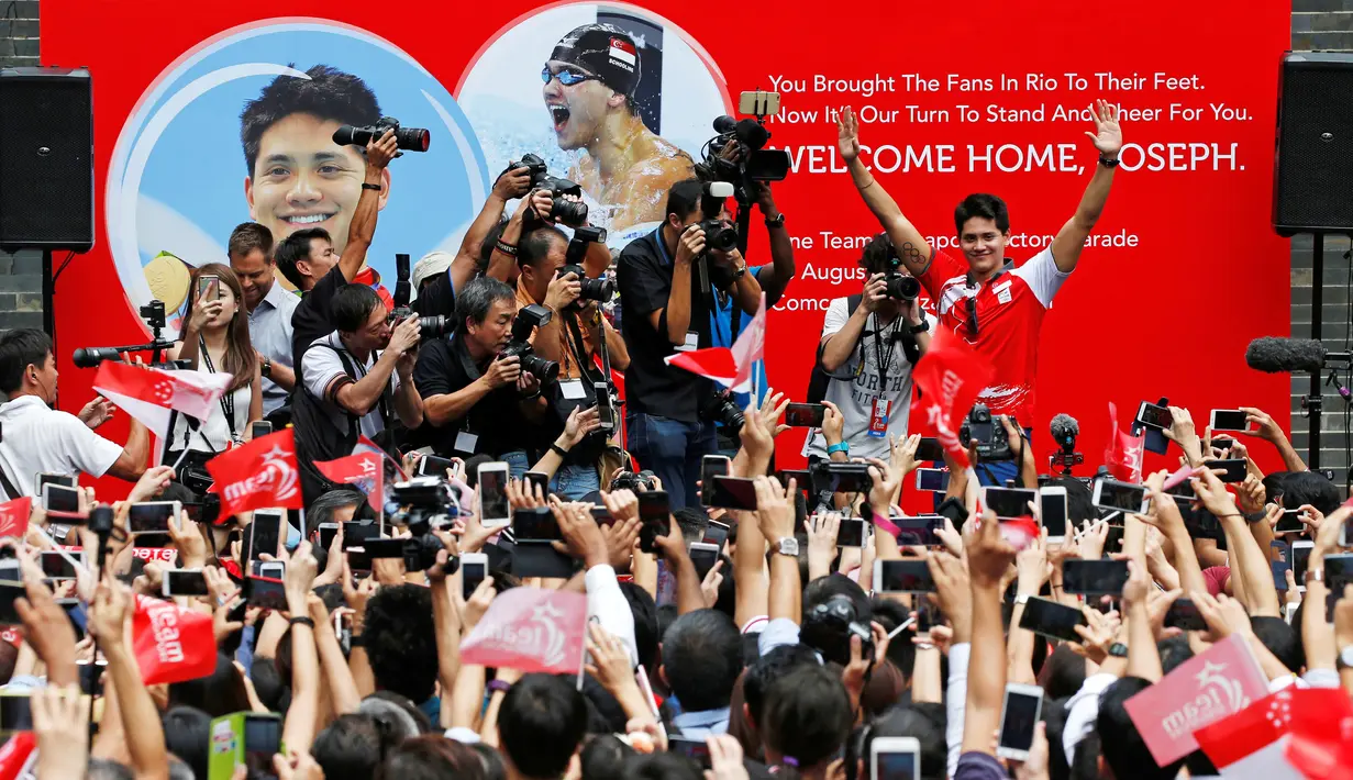 Atlet renang peraih medali emas Olimpiade Rio Brasil pertama dari Singapura, Joseph Schooling menyapa ribuan warga di atas podium usai melakukan parade di Singapura (18/08). (REUTERS/Edgar Su)