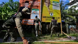 Petugas Satpol PP mencopot ratusan APK dan bendera partai yang terpasang tak sesuai aturan. (CHAIDEER MAHYUDDIN/AFP)