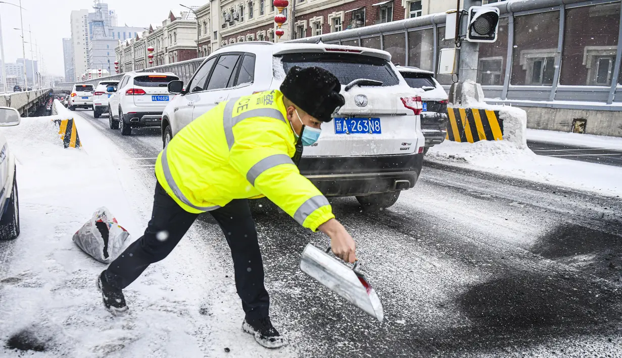 Polisi menyebarkan abu di jalan agar tidak terlalu licin di tengah hujan salju di Urumqi, ibu kota Daerah Otonom Uighur Xinjiang, China barat laut, pada 19 November 2020. Hujan salju yang terus turun selama berhari-hari telah menyebabkan jalanan di Kota Urumqi basah dan licin. (Xinhua/Wang Fei)
