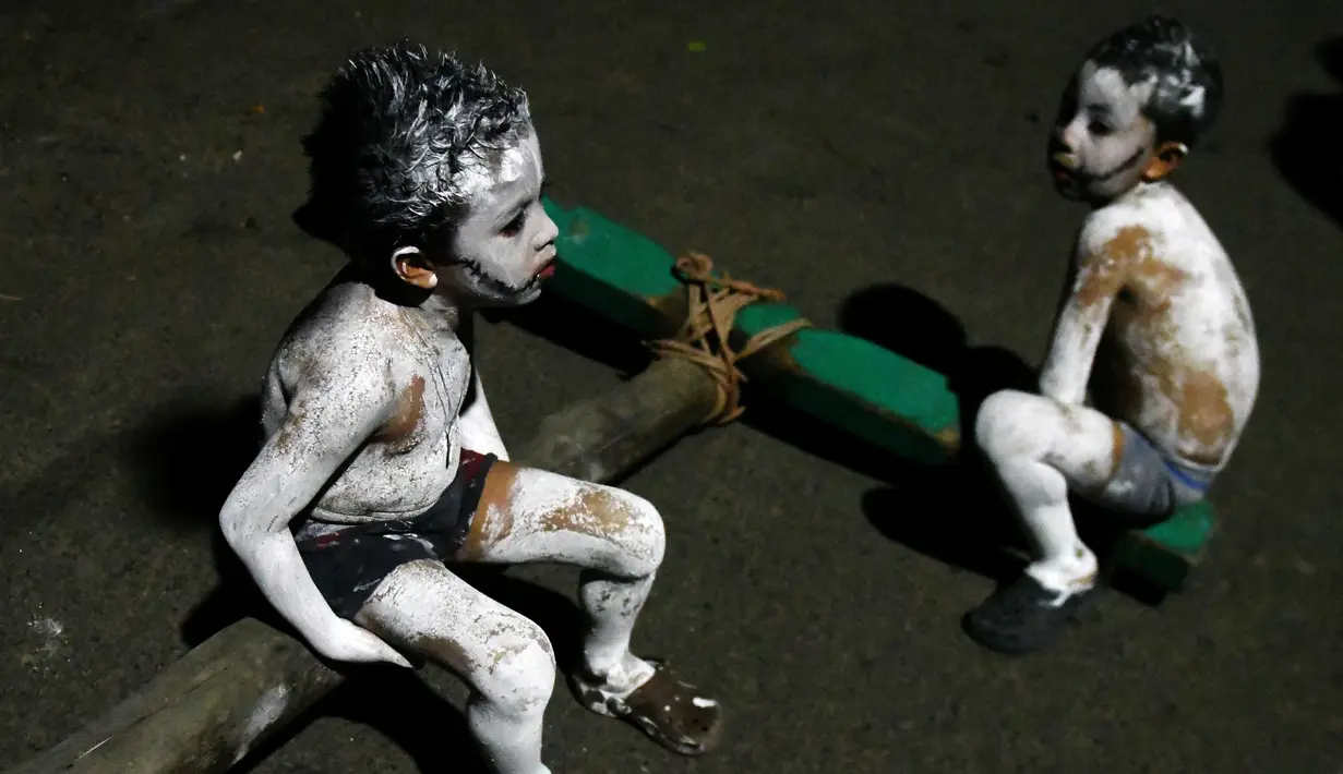 Dua orang bocah dengan tubuh dipenuhi cat putih mengikuti La Calabiuza di Tonacatepeque, El Salvador (1/11). (AFP Photo/Marvin Recinos)
