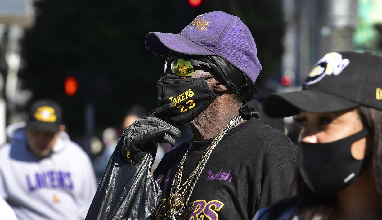 Dua orang fans berdiri di depan tugu peringatan di dekat Staples Center, Los Angeles, California, Selasa (26/1/2021) untuk mengenang 1 tahun meninggalnya bintang LA Lakers, Kobe Bryant bersama putrinya, Gianna dalam sebuah tragedi kecelakaan helikopter. (AFP/Frederic J. Brown)