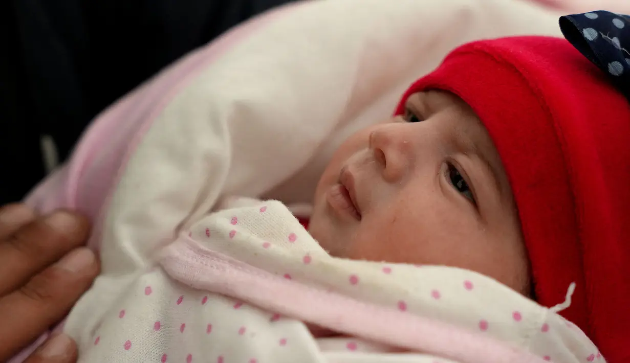 Khalil al-Suwadi menggendong keponakannya Afraa, bayi Suriah yang lahir di bawah reruntuhan setelah gempa bumi 6 Februari yang melanda Turki dan Suriah yang menewaskan orang tua dan saudara kandungnya, di kota Jindayris yang dikuasai pemberontak di Suriah utara, Selasa (21/2/2023). Khalil al-Suwadi menikah dengan saudara perempuan mendiang ayah bayi itu, yang juga sepupunya. (Rami al SAYED / AFP)