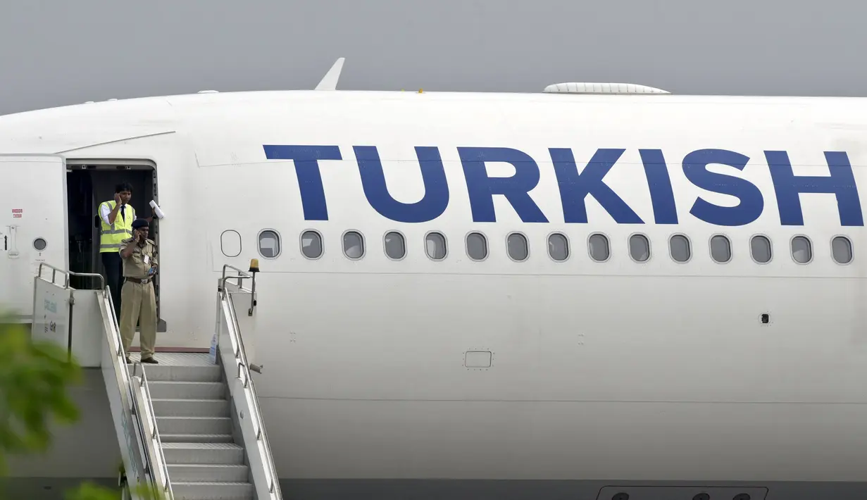 Petugas keamanan yang keluar pesawat Turkish Airlines melakukan percakapan dengan telepon selular usai pendaratan darurat di New Delhi, Selasa (7/7/2015). Pendaratan dilakukan karena teror bom secara tertulis di sebuah toilet pesawat. (REUTERS/Stringer)