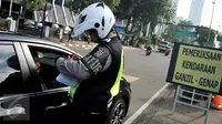 Petugas menilang pengendara mobil berpelat genap yang melintas pada tanggal ganjil di Bundaran Senayan, Jakarta, Rabu (31/8). Sejak kemarin mulai diberlakukan sanksi kepada pengendara yang melanggar aturan ganjil-genap. (Liputan6.com/Gempur M Surya)