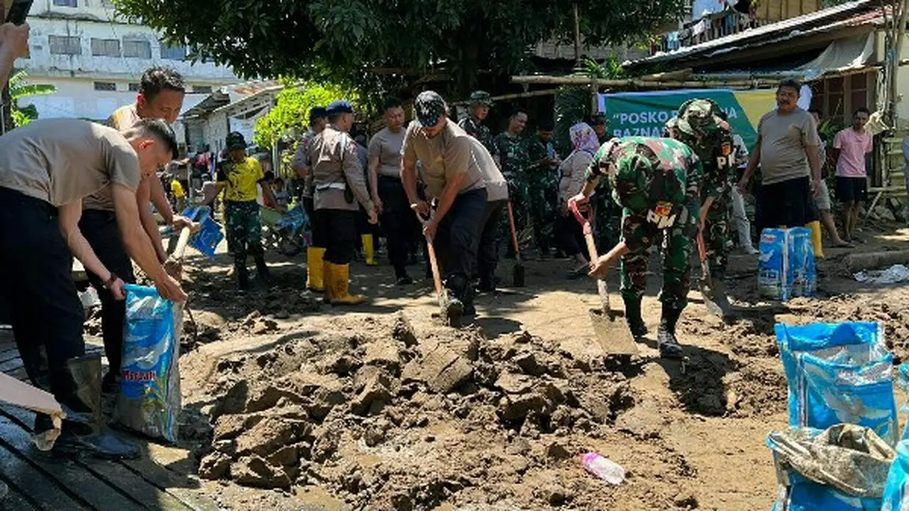 Personil TNI dan Polri, Senin (30/1/2023), membantu warga membersihkan material sisa banjir dan longsor di Manado.