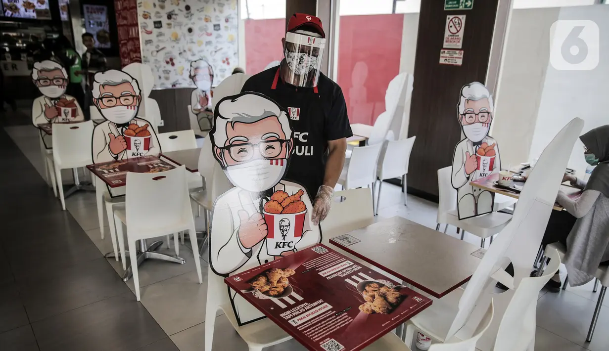 Pelayan merapikan banner bergambar karakter di KFC Salemba, Jakarta, Selasa (23/6/2020). Banner bergambar tersebut berguna untuk pembatas bagi pengunjung yang makan di tempat saat fase kenormalan baru. (Liputan6.com/Faizal Fanani)