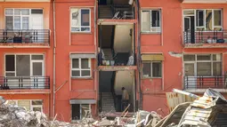 Seorang pria menaiki tangga blok apartemen yang rusak sebagian di samping bangunan yang hancur pascagempa di Samandag, Turki selatan, Rabu, 22 Februari 2023. Korban selamat dari gempa yang mengguncang Turki dan Suriah 15 hari lalu, menewaskan puluhan ribu orang dan menyebabkan ratusan ribu lainnya kehilangan tempat tinggal , menghadapi lebih banyak trauma dan kehilangan setelah gempa mematikan dan gempa susulan mengguncang wilayah tersebut. (AP Photo/Emrah Gurel)