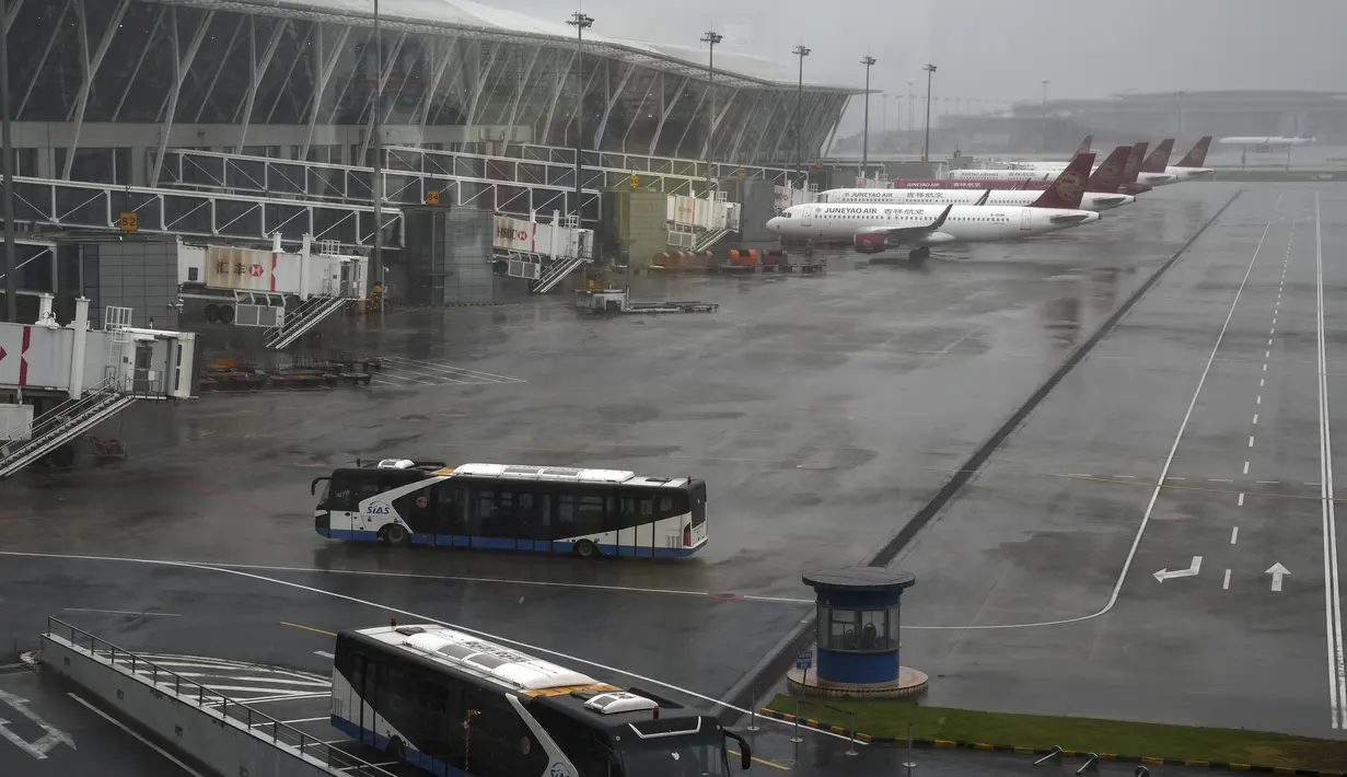 Bus dan pesawat penumpang diparkir di landasan setelah semua penerbangan dibatalkan di Bandara Internasional Pudong, Shanghai, Minggu (25/7/2021). China telah menutup jalur kereta api dan pelabuhan, serta membatalkan jadwal penerbangan sebelum topan In-Fa diperkirakan mendarat. (AP Photo/Andy Wong)