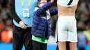 Striker Portugal Cristiano Ronaldo melepas jerseynya untuk fans cilik pada akhir laga Grup A Kualifikasi Piala Dunia 2022 Zona Eropa melawan Irlandia di Stadion Aviva, Jumat (12/11/2021) dinihari WIB. Penggemar cilik itu nekat menerobos masuk lapangan untuk bertemu Ronaldo. (Paul Faith / AFP)