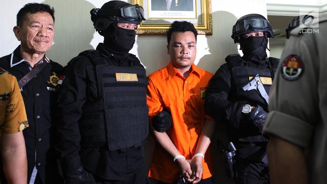 Polisi mengawal tersangka pembunuhan satu keluarga di Kota Bekasi saat gelar perkara di Polda Metro Jaya, Jakarta, Jumat (16/11). Tersangka HS mengaku telah melakukan pembunuhan tersebut. (Merdeka.com/Imam Buhori)