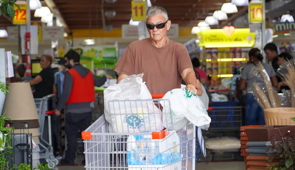 Seorang pria membeli perbekalan dan makanan yang tidak mudah rusak di supermarket sebagai persiapan menghadapi datangnya Badai Tropis Ernesto, di San Juan, Puerto Riko, Selasa (13/8/2024). (Jaydee Lee SERRANO / AFP)