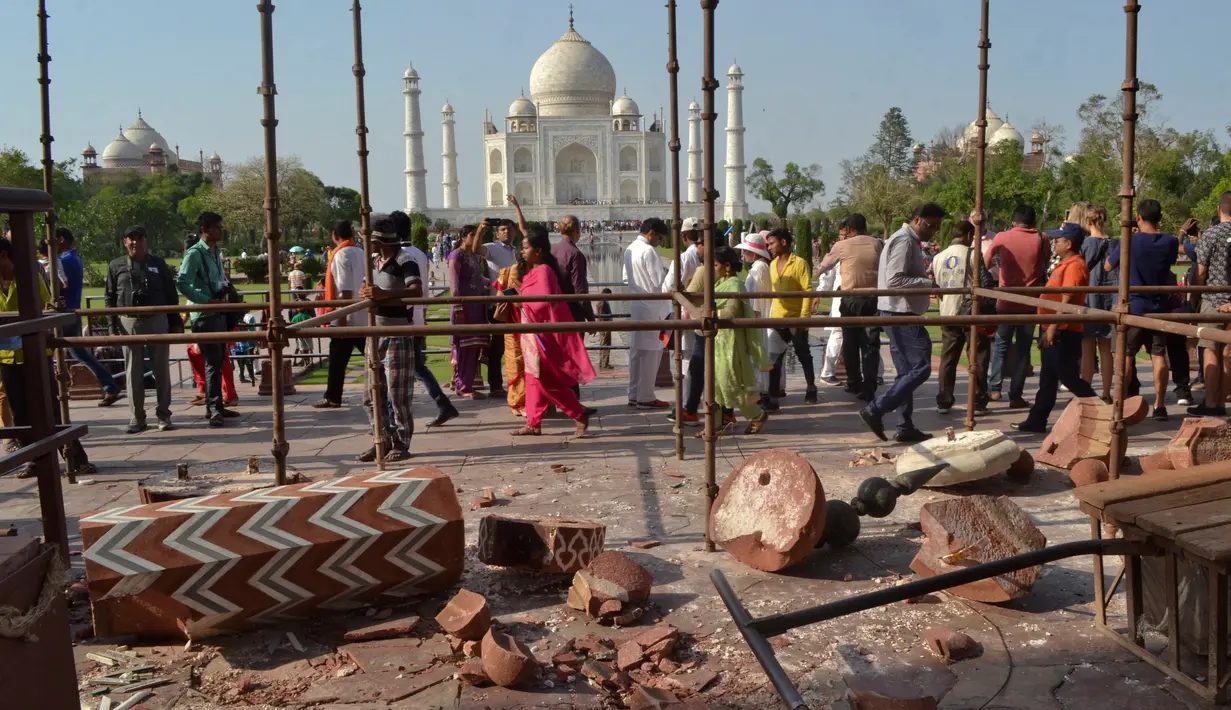 Wisatawan berjalan melewati reruntuhan puing-puing dari pilar Taj Mahal yang roboh di pintu masuk bangunan ikonik tersebut di Agra, India, Kamis (12/4). Dua buah pilar menara Taj Mahal rusak akibat dihantam angin kencang. (AP/Pawan Sharma)