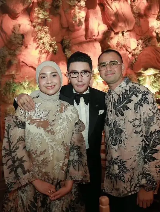 Nagita dengan dress warna cream dengan bordiran batik yang mewah. Penampilannya dilengkapi pashmina warna senada. Sedangkan Raffi tampil dengan kemeja panjang batik dan celana panjang hitamnya.  [@raffinagita1717].