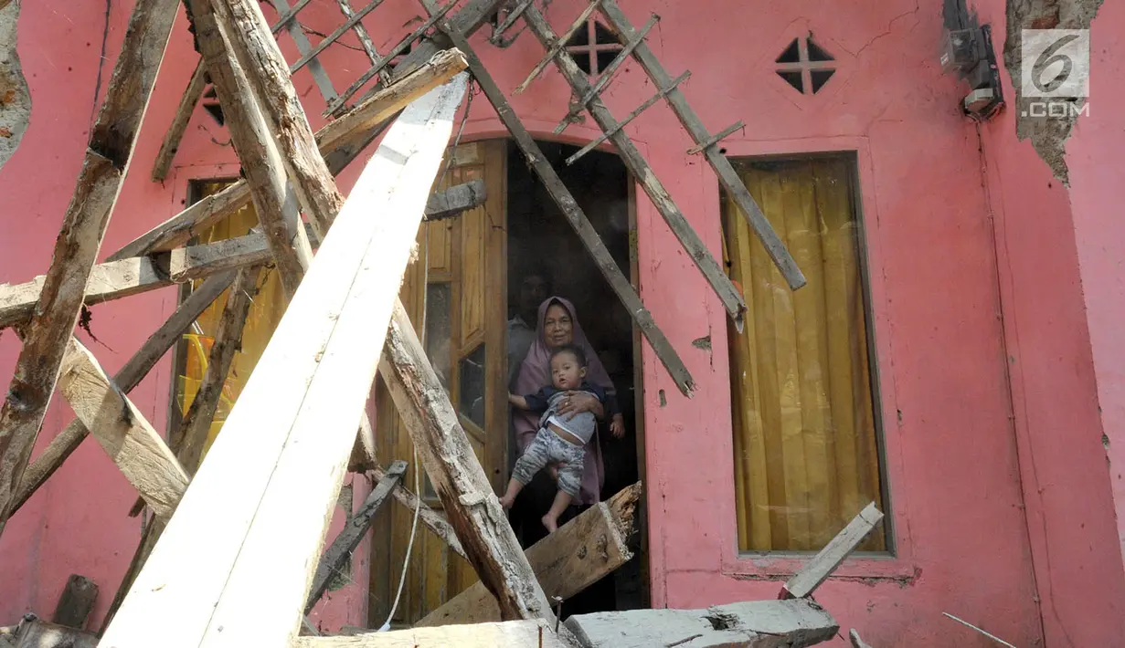 Warga berdiri di pintu rumahnya yang hancur setelah gempa mengguncang Mandalawangi, Pandeglang, Banten, Sabtu (3/8/2019).  Jumlah bangunan rusak akibat gempa berkekuatan 6,9 magnitudo yang mengguncang Banten terus bertambah. (merdeka.com/Arie Basuki)