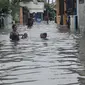 Warga menuntun anaknya melewati banjir yang mencapai pinggang orang dewasa di Rawa Buaya, Jakarta, Minggu (28/2/2016). Banjir terjadi akibat luapan Kali Mookervart yang diguyur hujan sejak malam. (Liputan6.com/Gempur M Surya)