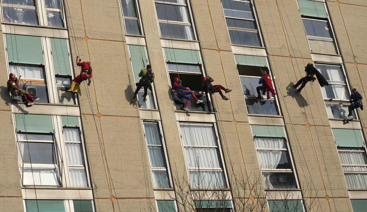 Sejumlah orang berpakaian superhero turun dari atap memberi kejutan di jendela kamar pasien anak di bangsal Pediatri rumah sakit San Paolo di Milan, Italia, Rabu (15/12/2021). Saat beraksi, para superhero memanjat dengan menggunakan tali dibekali alat pengaman yang lengkap. (AP Photo/Luca Bruno)