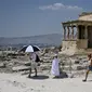 Turis menggunakan payung untuk melindungi diri dari sinar matahari saat mengunjungi Acropolis di Athena, Yunani, Minggu (24/7/2022). Negara ini berada dalam cengkeraman gelombang panas yang dimulai pada 23 Juli dan akan berlangsung beberapa hari. Suhu diperkirakan akan mencapai 42 derajat Celcius (107 derajat Fahrenheit) di beberapa daerah. (Louisa GOULIAMAKI / AFP)