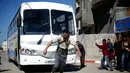 Mohamed Barka, pria yang dijuluki "Super Hero" asal Palestina menarik sebuah bus dengan tali yang terikat di tubuh dalam aksinya di Deir Al-Balah, Gaza Tengah, Kamis (4/2). (MOHAMMED ABED/AFP)