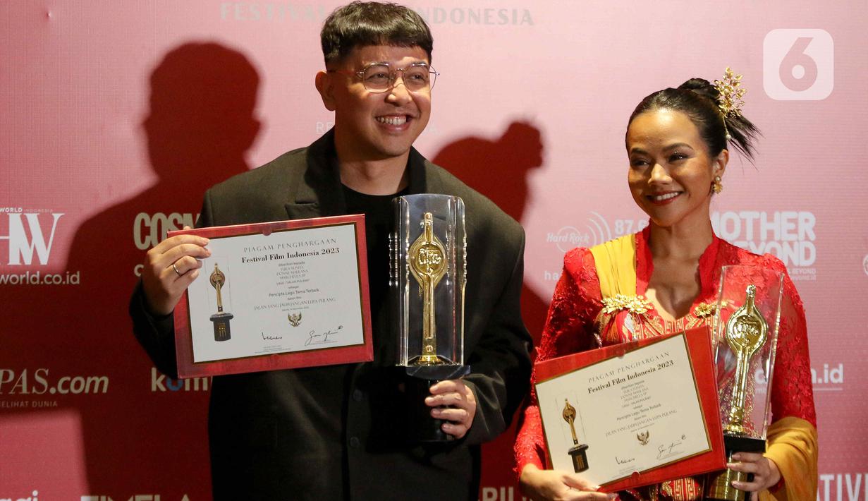 Penyanyi Yura Yunita (kanan) bersama Donne Maulana  berpose memegang piala saat menerima Anugerah Festival Film Indonesia (FFI) 2023 kategori Pencipta Lagu Tema Terbaik di Ciputra Artpreneur, Jakarta, Selasa (14/11/2023). (Liputan6.com/Herman Zakharia)