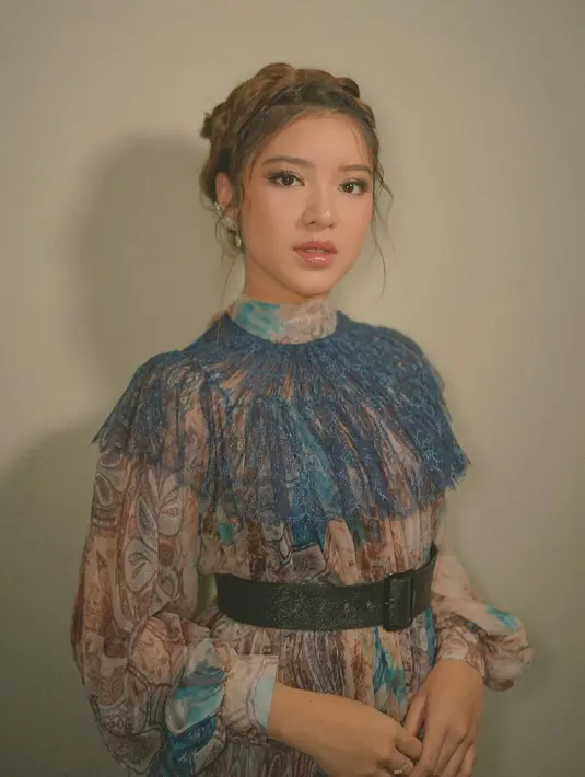 Tiara Andini juga cocok dengan mengenakan dress bergaya Victorian. Dress bermotif ini dilengkapi dengan lace berwarna biru dan belt berwarna hitam. Rambut yang ditata bergaya up do dengan sentuhan akhir kepang.