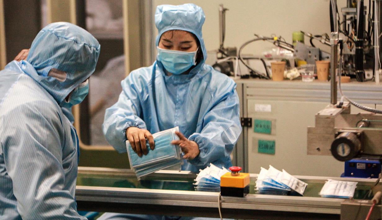 Pekerja memproduksi masker di sebuah pabrik di Yangzhou, Provinsi Jiangsu, China, Senin (27/1/2020). Masker tersebut diproduksi untuk mendukung pasokan bahan medis saat wabah virus corona melanda China. (STR/AFP)