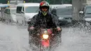 Pengendara sepeda motor menerjang genangan air akibat hujan lebat di Manila, Filipina, Kamis (27/7). Pihak Biro Cuaca setempat memberi peringatan agar warga terus berhati-hati beraktivitas di luar rumah selama musim penghujan. (AP/Bullit Marquez)