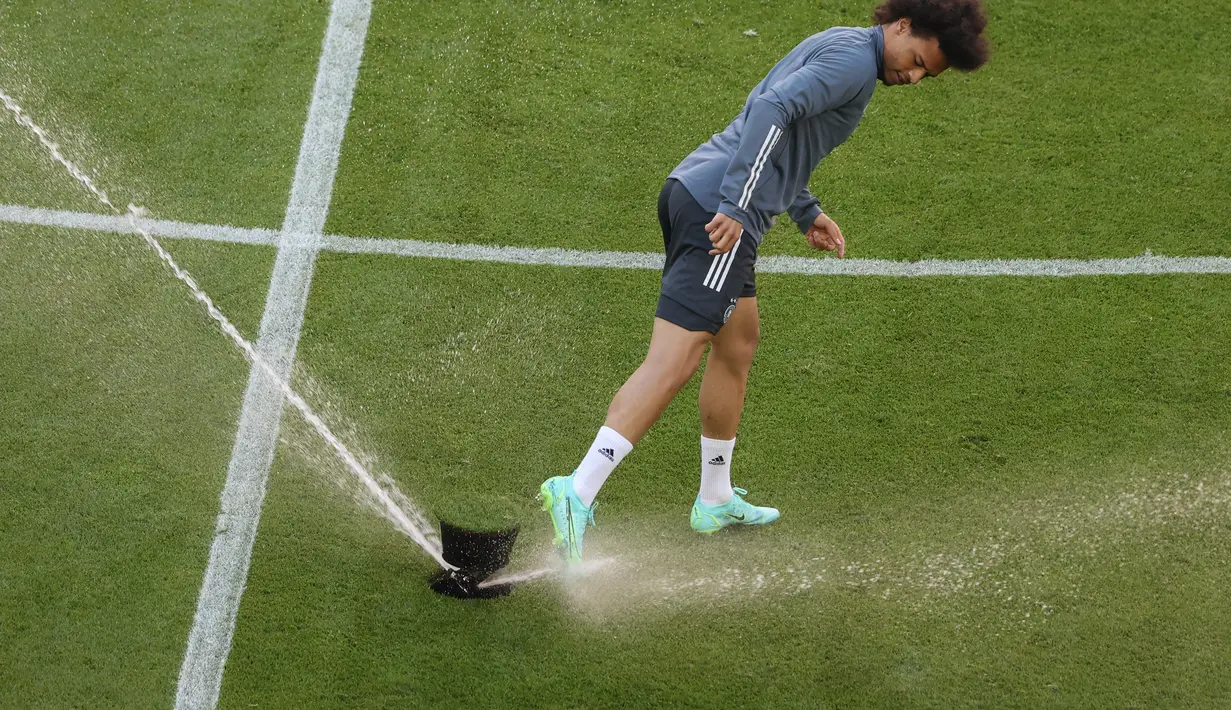 Gelandang Jerman Leroy Sane bermain dengan sprinkler menyiram rumput selama sesi latihan MD-1 di Allianz Arena di Munich (14/6/2021). Pertandingan dari grup neraka ini akan berlangsung di Allianz Arena, Munich, Jerman pada Rabu (16/6) dini hari pukul 02.00 WIB. (AFP/Franck Fife)