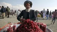 Seorang pria menjual buah delima di taman umum selama perayaan Nowruz, Tahun Baru Persia, di Kabul, Afghanistan, (21/3). Nowruz dirayakan pada hari pertama musim semi di negara-negara termasuk Afghanistan, Tajikistan, dan Iran. (AP Photo/Massoud Hossaini)