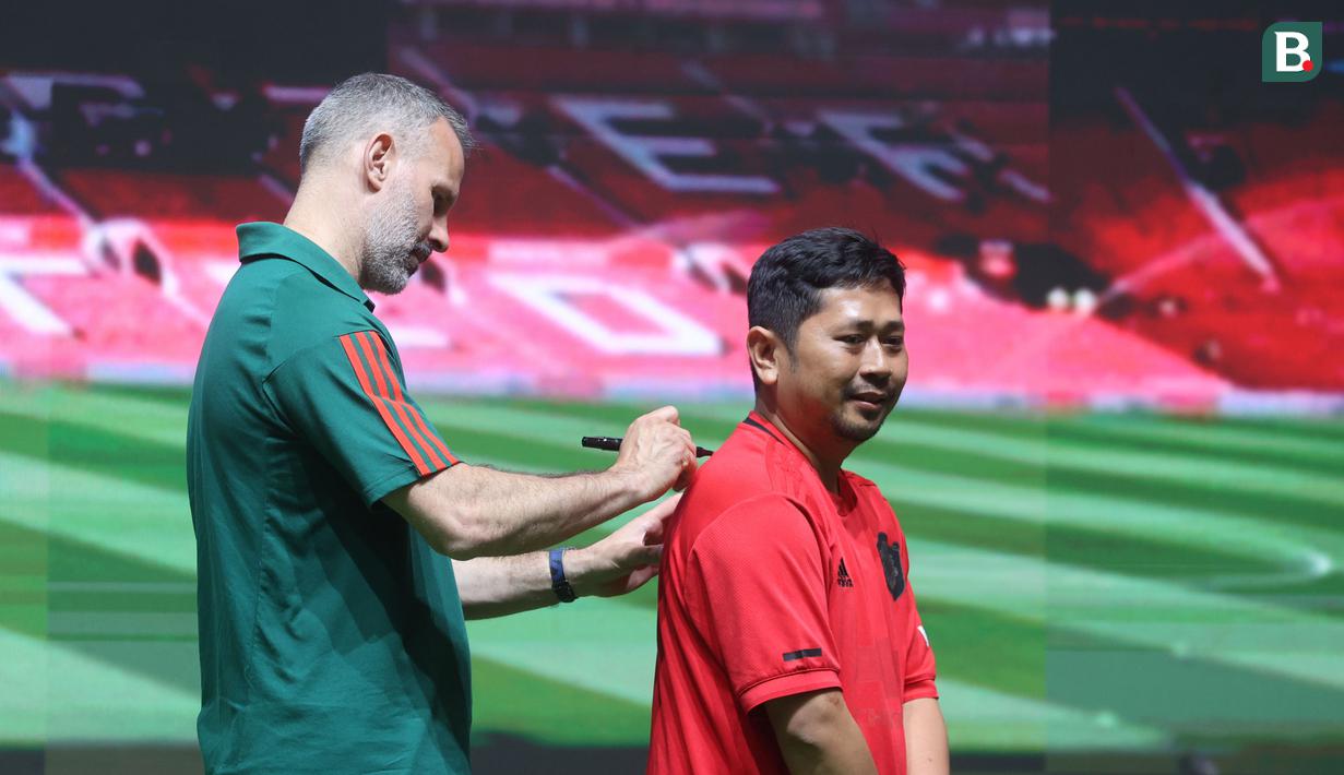 Legenda Manchester United (MU), Ryan Giggs, membubuhkan tanda tangan di jersey fans dalam acara peluncuran kartu kredit Maybank yang berkolaborasi dengan MU di Jakarta Convention Center (JCC), Senayan, Jakarta, Sabtu (18/5/2024). (Bola.com/M Iqbal Ichsan)