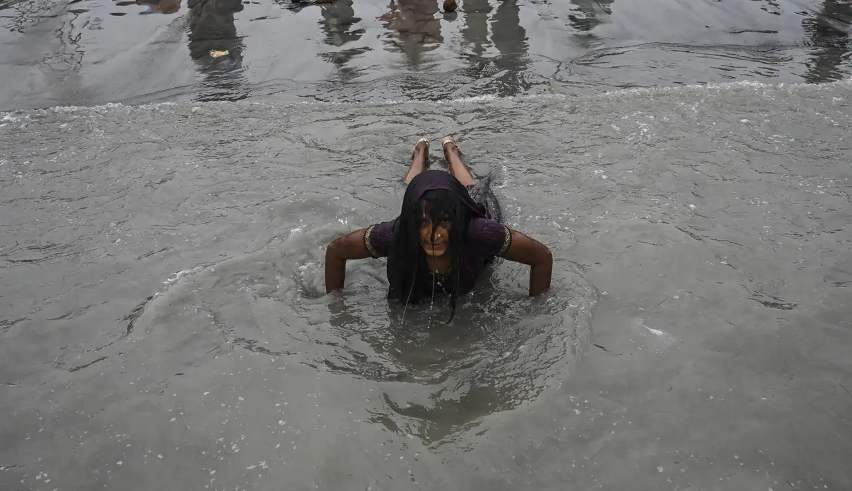 Seorang peziarah Hindu berenang selama festival Makar Sankranti di pertemuan Sungai Gangga dan Teluk Benggala di Pulau Sagar, selatan Kolkata (14/1/2022). Puluhan ribu umat Hindu di India, yang dipimpin kepala kuil dan para pertapa, mengikuti ritual suci di Sungai Gangga. (AFP/Dibyangshu Sarkar)