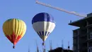 Pekerja bangunan gedung memperhatikan balon udara yang melitasinya Festival Balon Internasional ke-XV di Metropolitan Park di Leon, negara bagian Guanajuato, Meksiko (20/11). (AFP/STR)