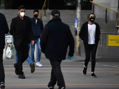 Orang-orang yang memakai masker berjalan di luar Stasiun Flinders Street di Melbourne, Kamis (23/7/2020). Sebagian penduduk kota terpadat kedua di Australia, Melbourne, mematuhi undang-undang baru yang mewajibkan pemakaian masker. (James Ross / AAP Image via AP)