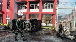 Petugas melintasi dampak kerusuhan di Lapas Narkotika Kelas III Langkat, Sumatera Utara, Kamis (16/5/2019). Akibat peristiwa kerusuhan yang dilakukan para narapidana di Lapas itu mengakibatkan tiga mobil dan dua sepeda motor petugas rusak terbakar dan ratusan napi melarikan diri. (Ivan Damanik/AFP)