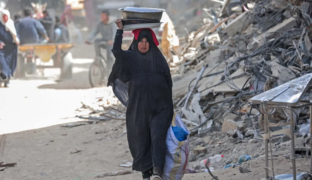 Seorang wanita Palestina membawa barang-barangnya di Khan Yunis di Jalur Gaza selatan pada 6 Maret 2024. Badan Bantuan dan Pekerjaan PBB (UNRWA) menyatakan bahwa rata-rata 63 perempuan terbunuh di Gaza setiap harinya, dan sekitar 37 diantaranya adalah ibu. (Foto: AFP)