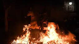 Seorang penunggang menginjakan kudanya diatas api unggun di desa San Bartolome de Pinares, Spanyol (16/1). Acara ini bertujuan untuk menghormati San Antonio Abad (Santo Anthony), santo pelindung hewan. (AFP Photo/Gabriel Bouys)